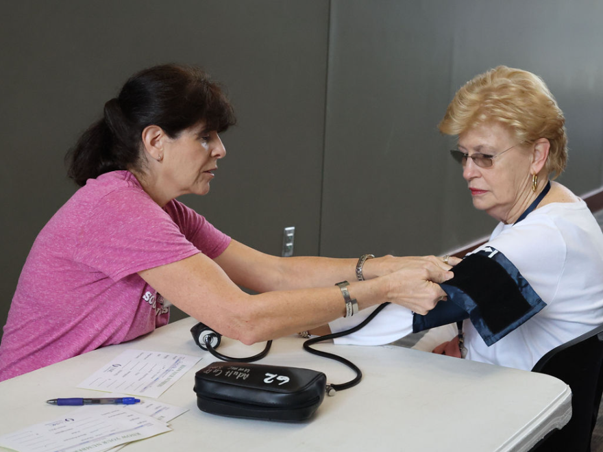 family nurse practitioner adjusts a blood pressure cuff on a participant at a health screening
